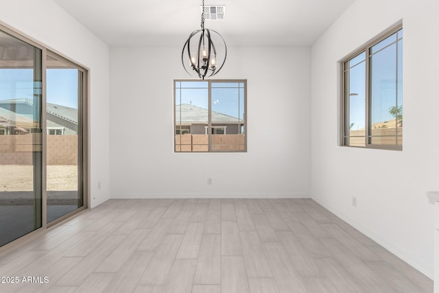 empty room with visible vents, light wood-style floors, a chandelier, and baseboards