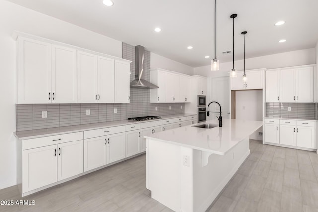 kitchen featuring white cabinets, backsplash, wall chimney range hood, and a sink