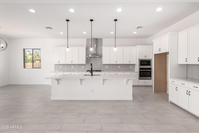kitchen featuring wall chimney range hood, light countertops, oven, backsplash, and built in microwave