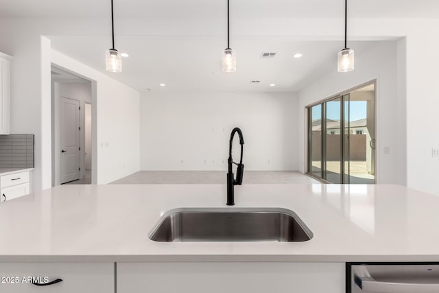 kitchen featuring a sink, white cabinetry, light countertops, stainless steel dishwasher, and open floor plan