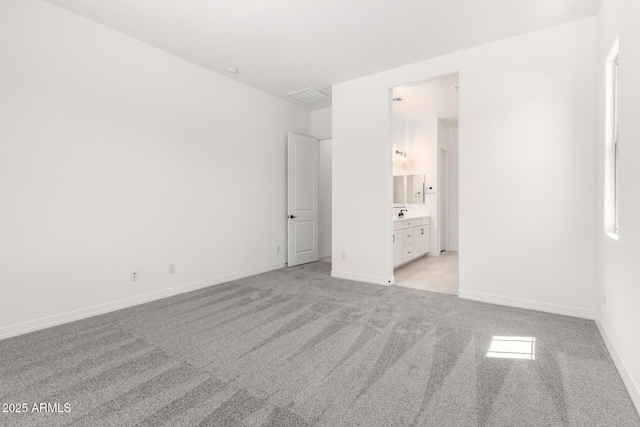 unfurnished bedroom featuring baseboards, visible vents, connected bathroom, and light colored carpet