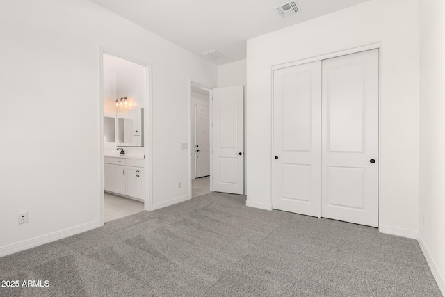 unfurnished bedroom with a closet, visible vents, baseboards, carpet floors, and ensuite bathroom