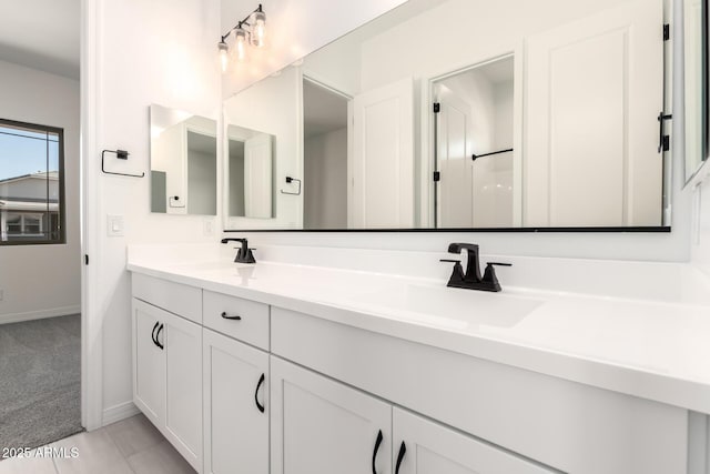 full bathroom featuring baseboards, double vanity, and a sink