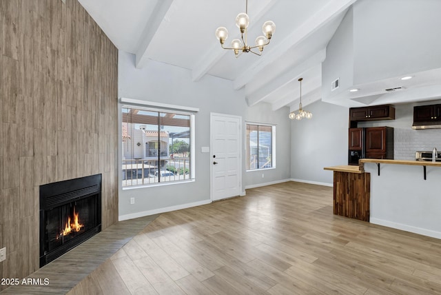 1017 E Maryland Ave Unit 236, Phoenix, AZ 85014 - unfurnished living room featuring visible vents, baseboards, beamed ceiling, a large fireplace, and a chandelier
