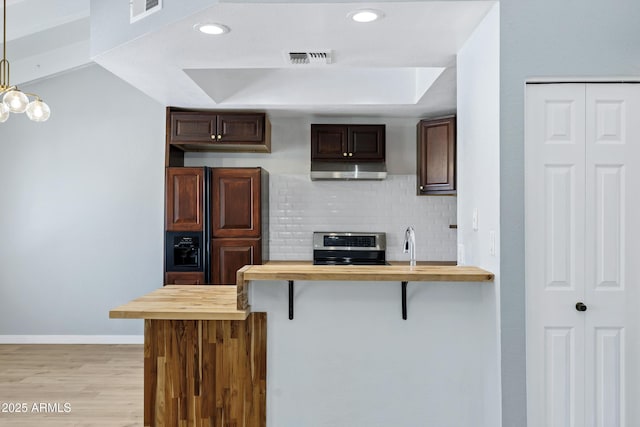1017 E Maryland Ave Unit 236, Phoenix, AZ 85014 - kitchen featuring butcher block countertops, a breakfast bar area, under cabinet range hood, visible vents, and electric stove