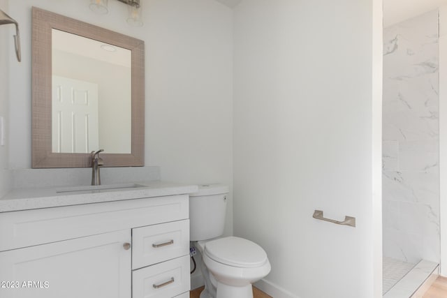 bathroom featuring tiled shower, vanity, and toilet