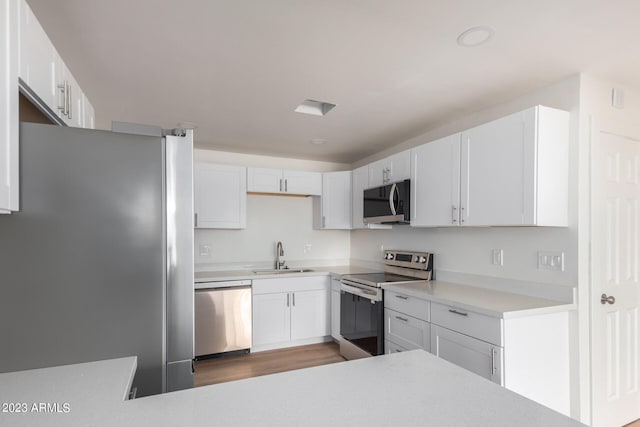 kitchen with light hardwood / wood-style flooring, stainless steel appliances, white cabinetry, and sink