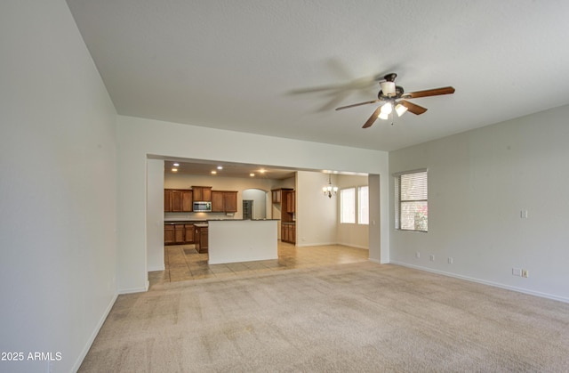 6192 S Claiborne Ave, Gilbert, AZ 85298 - unfurnished living room with light carpet, arched walkways, ceiling fan with notable chandelier, and baseboards