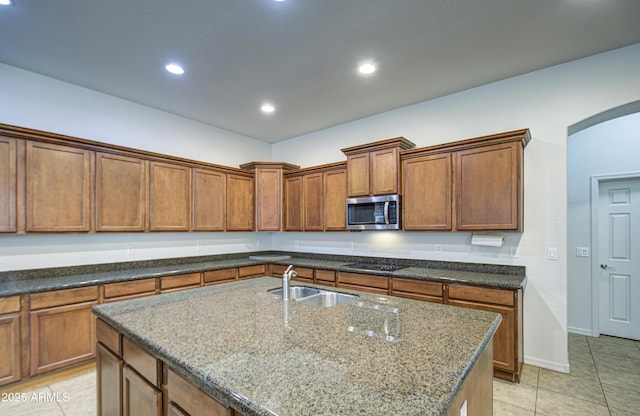 6192 S Claiborne Ave, Gilbert, AZ 85298 - kitchen with light tile patterned floors, arched walkways, stainless steel microwave, a sink, and black electric stovetop