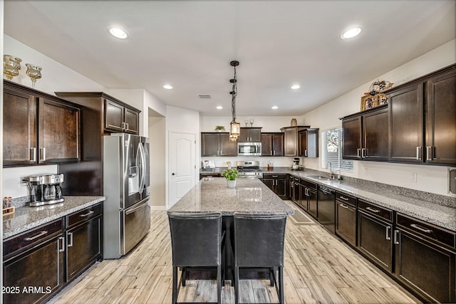 kitchen with sink, appliances with stainless steel finishes, dark brown cabinets, a center island, and decorative light fixtures