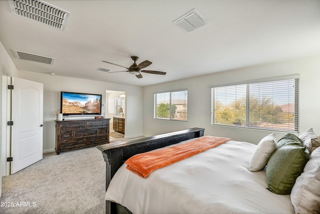 bedroom with ceiling fan, ensuite bath, and light carpet