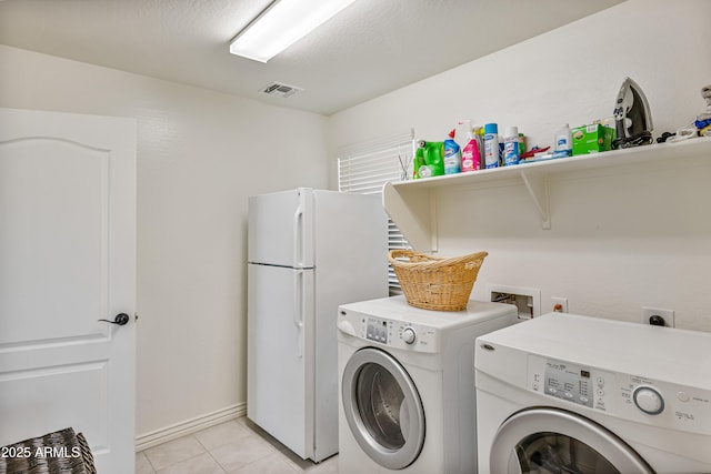 clothes washing area with independent washer and dryer and light tile patterned floors