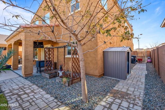 rear view of house featuring a storage shed and a patio area