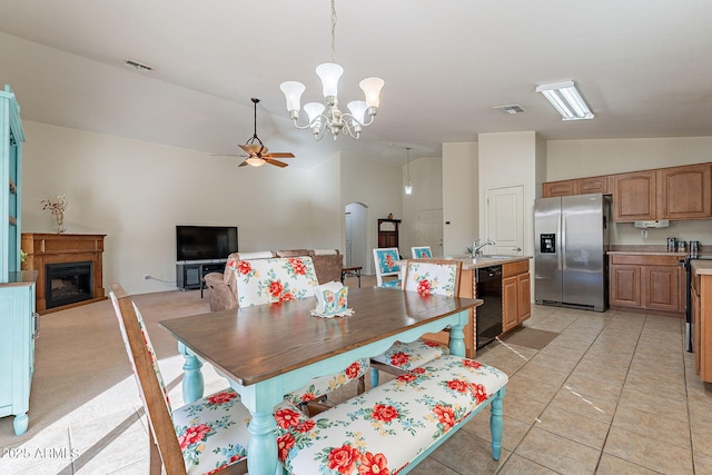 dining area with vaulted ceiling, ceiling fan with notable chandelier, sink, and light tile patterned floors