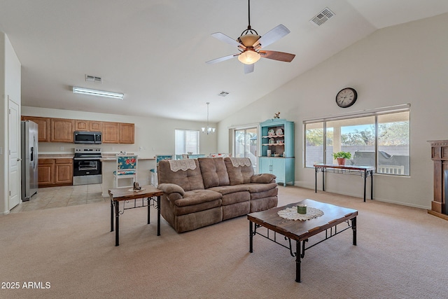 carpeted living room with ceiling fan with notable chandelier and high vaulted ceiling