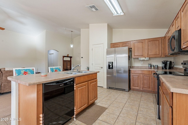 kitchen with pendant lighting, vaulted ceiling, black appliances, and a center island with sink