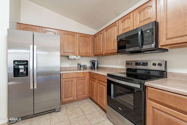 kitchen with vaulted ceiling, stainless steel appliances, and light tile patterned flooring