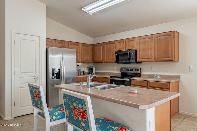 kitchen featuring light tile patterned flooring, appliances with stainless steel finishes, sink, and a center island with sink