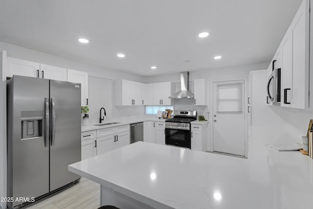 kitchen with tasteful backsplash, white cabinetry, wall chimney range hood, sink, and stainless steel appliances