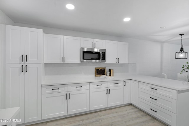 kitchen with white cabinets, light hardwood / wood-style flooring, and pendant lighting