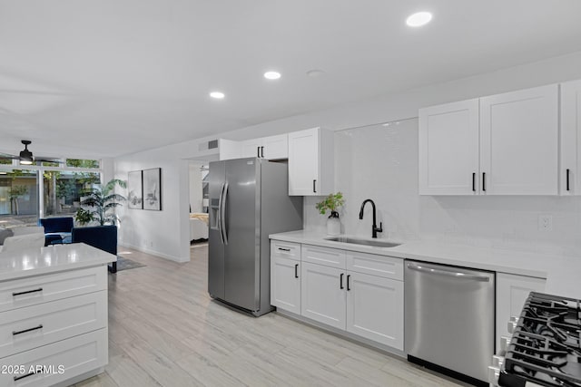 kitchen featuring sink, stainless steel appliances, white cabinetry, and light hardwood / wood-style floors