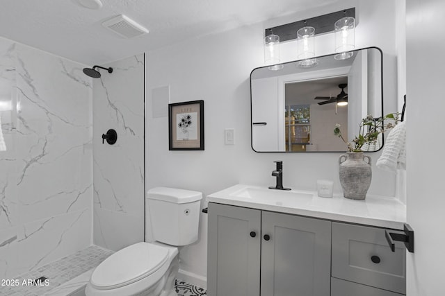 bathroom featuring a textured ceiling, vanity, toilet, ceiling fan, and tiled shower