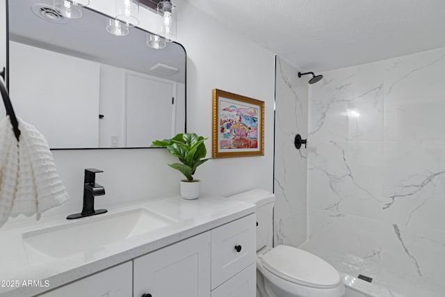 bathroom featuring a textured ceiling, tiled shower, toilet, and vanity