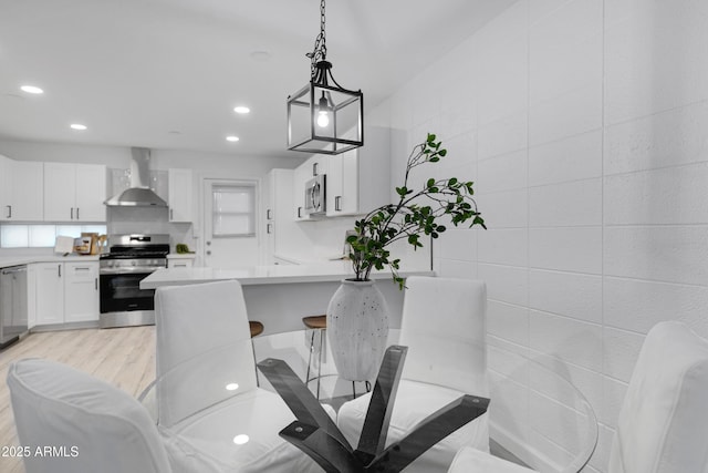 dining area with tile walls and light hardwood / wood-style flooring