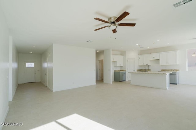 unfurnished living room featuring ceiling fan and sink