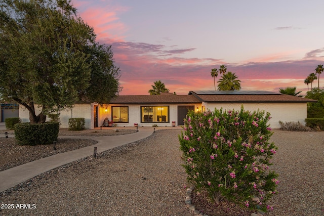 12866 W Orange Dr, Litchfield Park, AZ 85340 - view of front facade featuring a garage, solar panels, gravel driveway, and brick siding