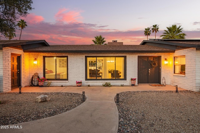 12866 W Orange Dr, Litchfield Park, AZ 85340 - view of front of house featuring a shingled roof, a chimney, and brick siding