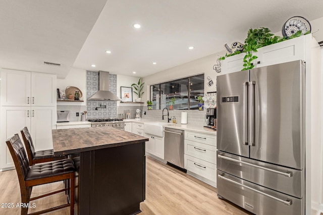 12866 W Orange Dr, Litchfield Park, AZ 85340 - kitchen with stainless steel appliances, wall chimney range hood, a sink, wood counters, and open shelves