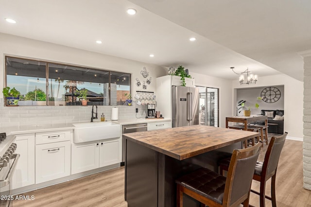 12866 W Orange Dr, Litchfield Park, AZ 85340 - kitchen with high quality appliances, a sink, a breakfast bar, butcher block counters, and backsplash