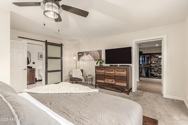 12866 W Orange Dr, Litchfield Park, AZ 85340 - bedroom with a barn door, carpet floors, a spacious closet, baseboards, and a ceiling fan