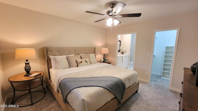 carpeted bedroom featuring a walk in closet, ceiling fan, and ensuite bathroom