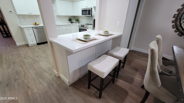 kitchen with white cabinets, stainless steel appliances, a kitchen breakfast bar, and kitchen peninsula