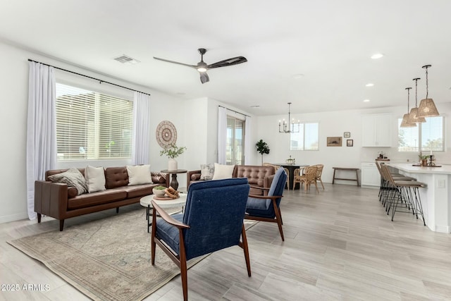 living room featuring ceiling fan with notable chandelier