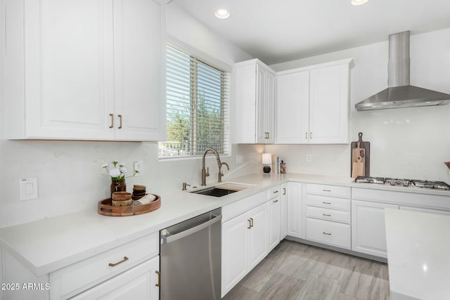 kitchen featuring wall chimney exhaust hood, white gas stovetop, white cabinetry, sink, and stainless steel dishwasher