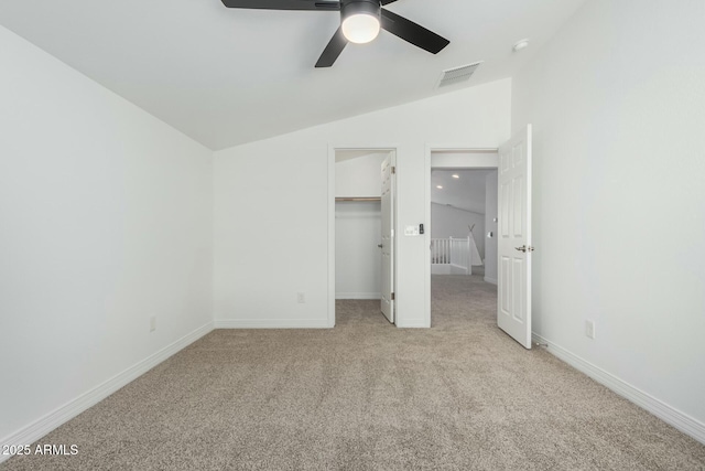 unfurnished bedroom with a spacious closet, lofted ceiling, light carpet, a closet, and ceiling fan