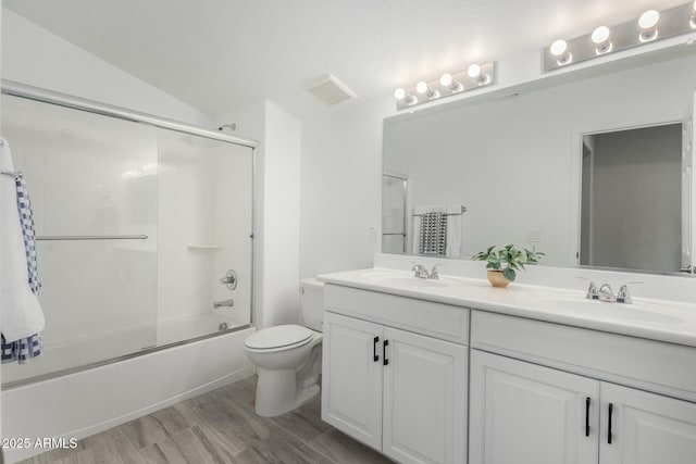 full bathroom featuring wood-type flooring, vaulted ceiling, toilet, vanity, and bath / shower combo with glass door