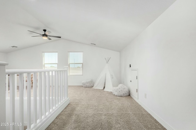 interior space with vaulted ceiling, ceiling fan, a crib, and carpet floors