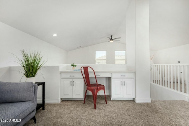 office area featuring light colored carpet, vaulted ceiling, and built in desk