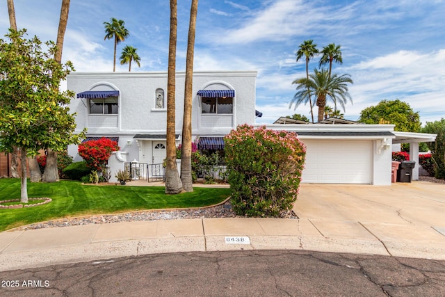 view of front of property with stucco siding, an attached garage, concrete driveway, and a front yard