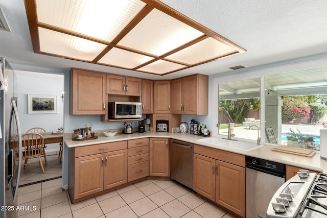 kitchen featuring light countertops, light tile patterned floors, appliances with stainless steel finishes, and a sink
