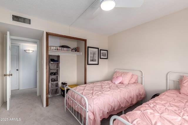 carpeted bedroom featuring visible vents, a textured ceiling, a closet, and ceiling fan