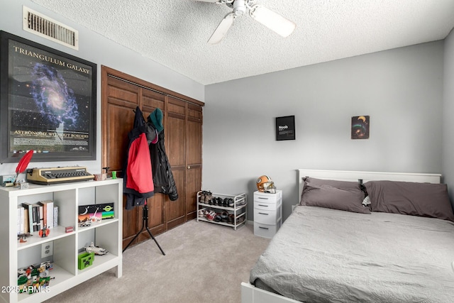 bedroom with visible vents, light carpet, a ceiling fan, a textured ceiling, and a closet