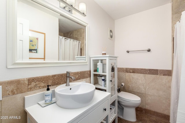 full bathroom featuring tile patterned flooring, toilet, vanity, wainscoting, and tile walls