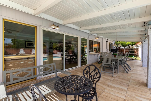 wooden terrace featuring outdoor dining area, a patio, and a fenced in pool