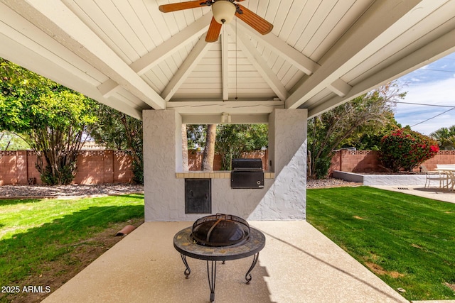 view of patio / terrace featuring area for grilling, a ceiling fan, a fenced backyard, an outdoor fire pit, and exterior kitchen