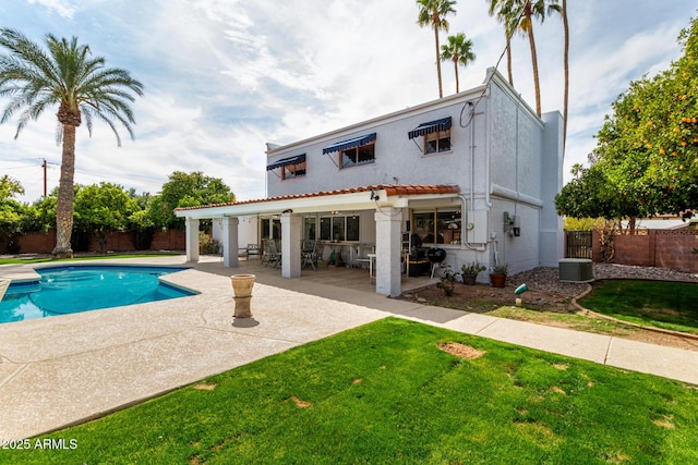 rear view of property with a patio, a fenced in pool, a yard, a fenced backyard, and stucco siding
